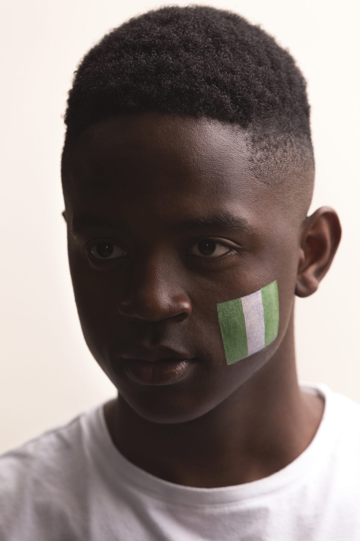 A young boy with the Nigerian flag painted on his cheek