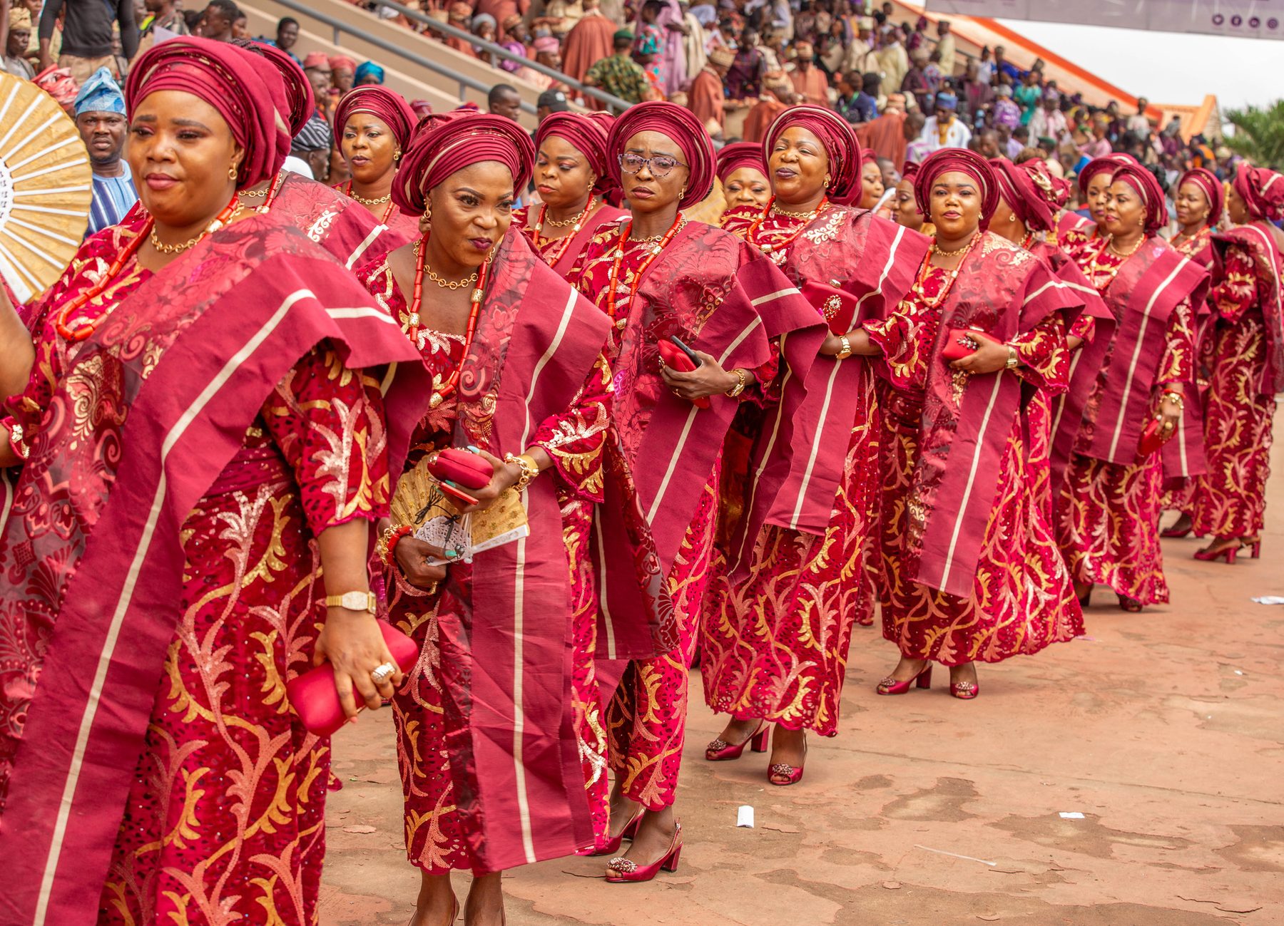 Women in vibrant red traditional attire at a Nigerian cultural festival procession